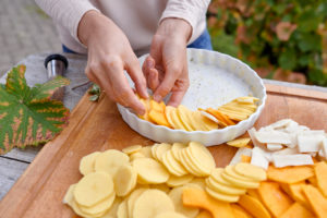 Prepare a gratin of potatoes, pumpkin and Jerusalem artichoke, arrange the sliced ingredients in a buttered baking pan Prepare a gratin of potatoes, pumpkin and Jerusalem artichoke, arrange the sliced ingredients in a buttered baking pan